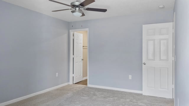 Empty bedroom with light blue walls, a ceiling fan, and a closet entrance.