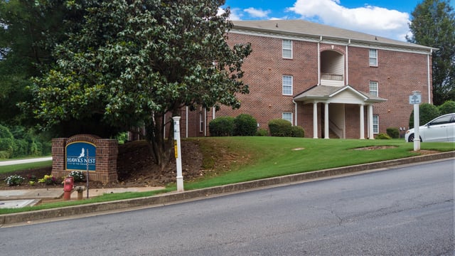 Hawks Nest apartment building exterior with brick facade and manicured lawn.