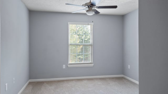 Empty bedroom with a ceiling fan and a window.