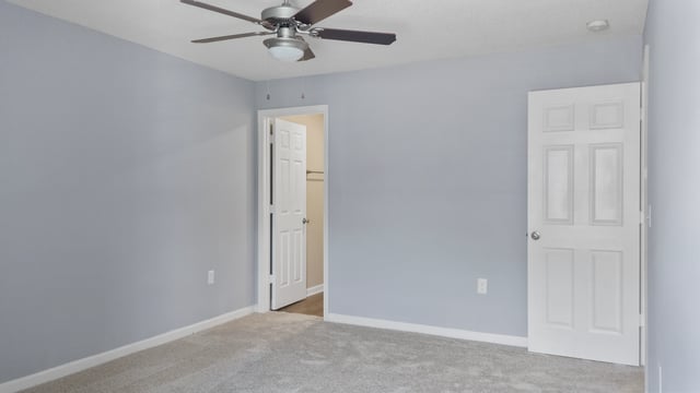 Bedroom with light blue walls, ceiling fan, and two doors.