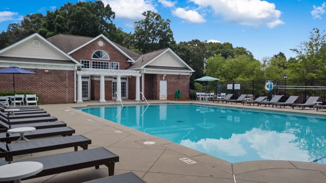 Resort-style swimming pool with lounge chairs and a red brick building.