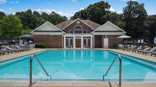 Outdoor swimming pool with lounge chairs and a clubhouse in the background.