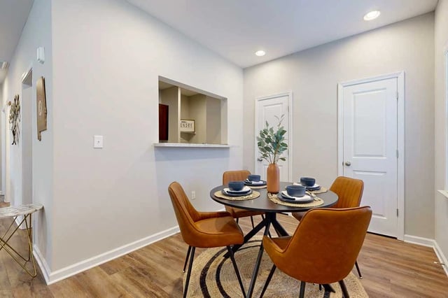 Dining area with a round table and four chairs in a modern apartment.