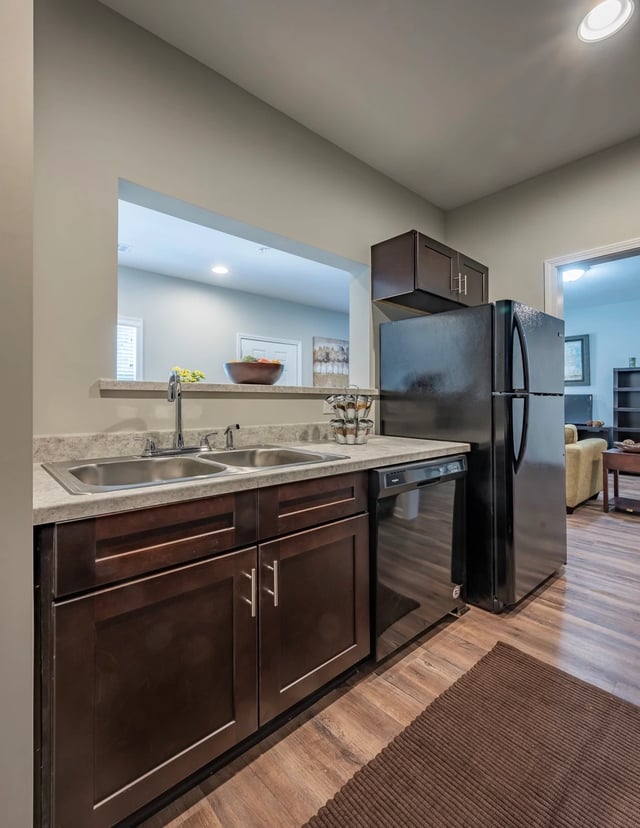 Modern kitchen with dark wood cabinets, stainless steel sink, and black refrigerator.