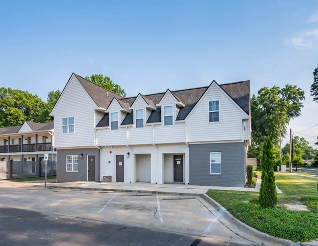 Exterior view of apartment buildings with parking lot in foreground.