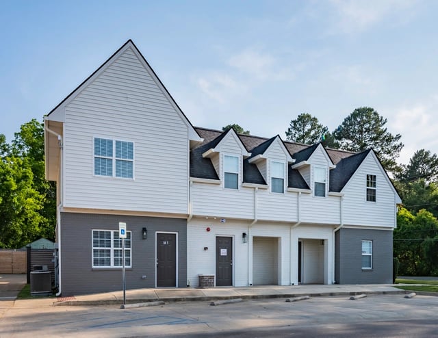 Exterior of apartment buildings with garages and parking lot.