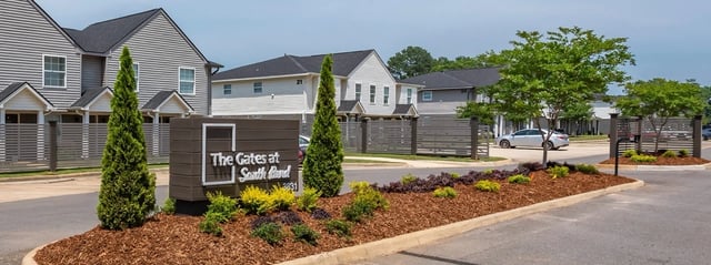 The Gates at South Bend monument sign and entrance with modern townhome buildings in the background.