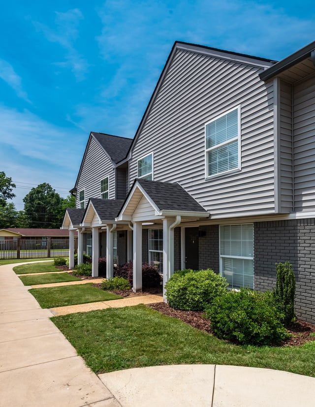 Exterior of apartment buildings with neat landscaping and a walkway.