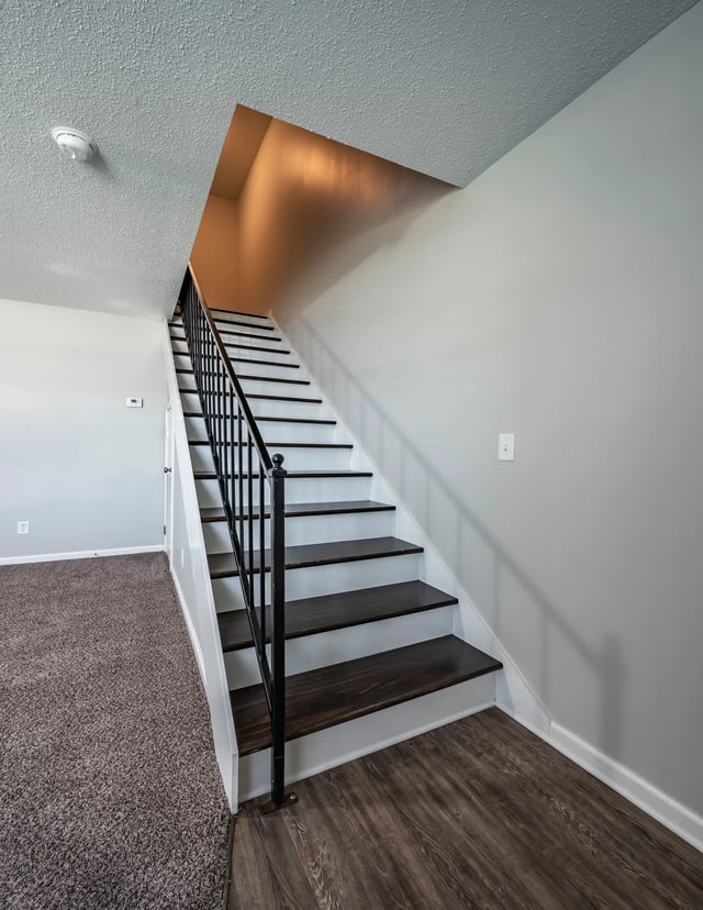 Staircase with dark wood steps and black railing.