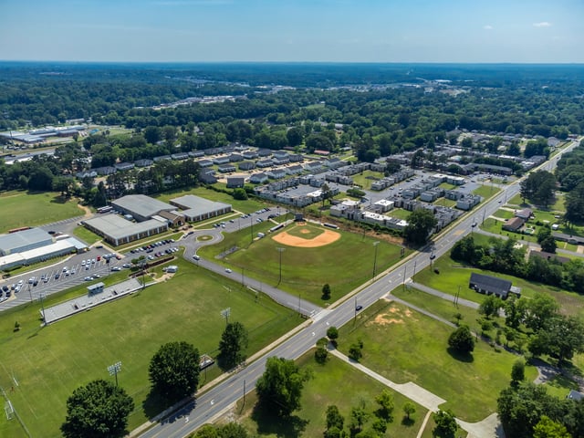 Aerial view of apartment buildings and a school campus with a baseball field.