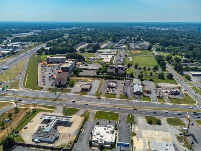 Aerial view of a suburban neighborhood with apartment buildings, a highway, and commercial areas.