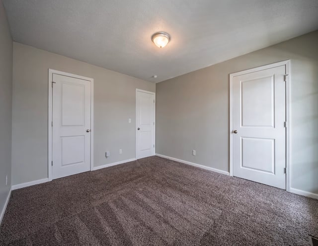 Empty bedroom with two white doors and neutral gray walls.