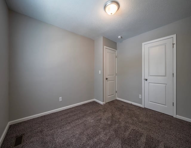 Bedroom with neutral gray walls and carpet, featuring two white doors.