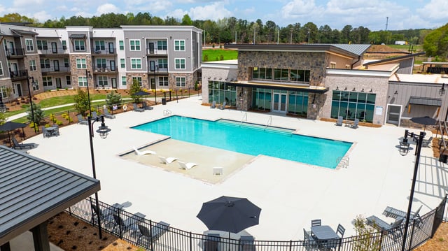 Aerial view of a resort-style swimming pool and modern apartment buildings.