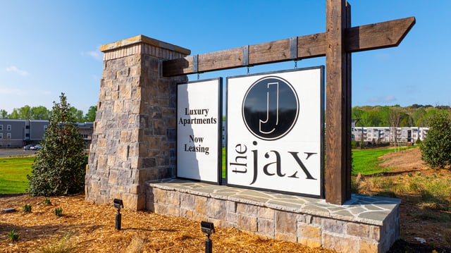 Signage for The Jax luxury apartments, indicating 'Now Leasing'.