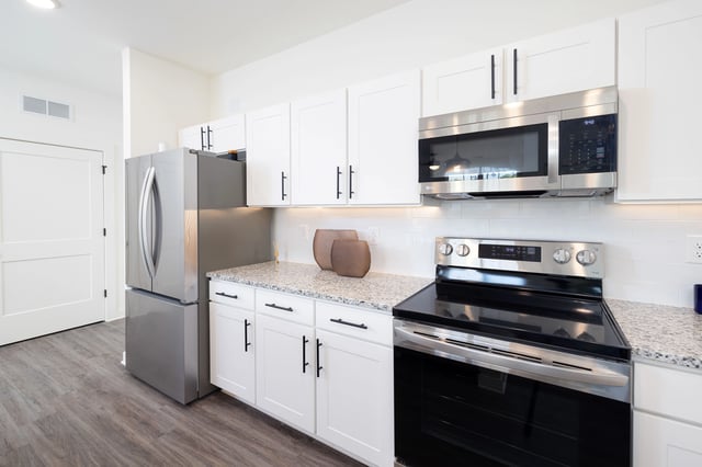 Modern kitchen with stainless steel appliances, white cabinets, and granite countertops.
