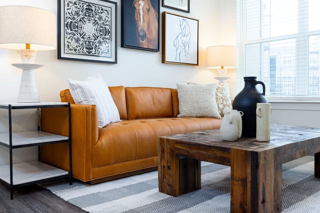 Modern living room with a tan leather sofa, coffee table, and decorative art.