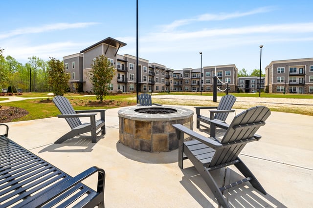 Outdoor fire pit area with seating and apartment buildings in the background.