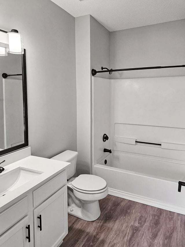 Modern bathroom with a white vanity, toilet, and bathtub with black fixtures.