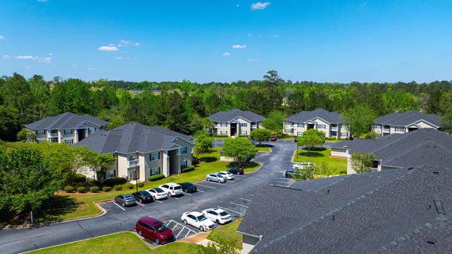 Aerial view of apartment buildings with parking lots and trees.