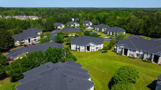 Aerial view of apartment buildings surrounded by green lawns and trees.