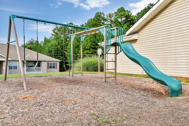 Children's playground with swings and a slide next to apartment buildings.