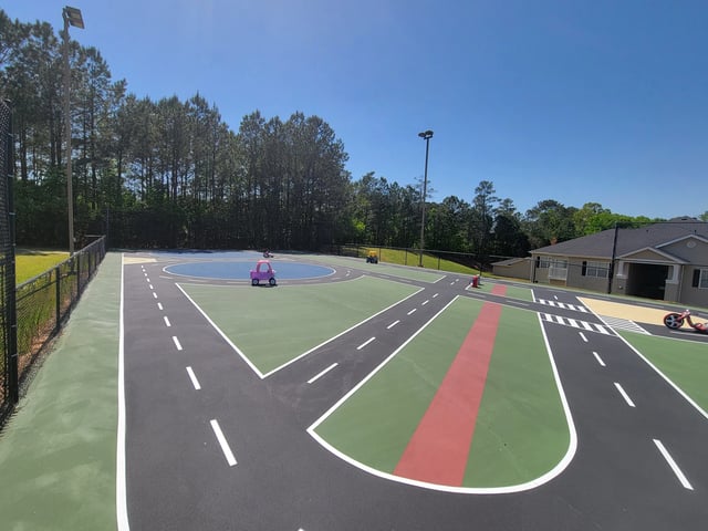 Outdoor play area designed like a miniature road system with toy cars and a scooter, providing a fun space for children.