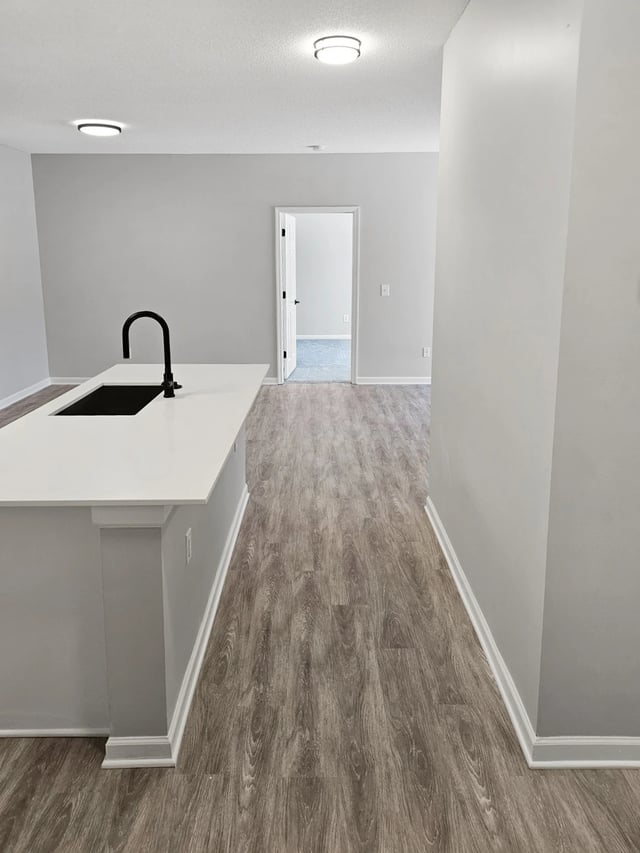 Kitchen island with sink and faucet, leading to a hallway with a doorway.
