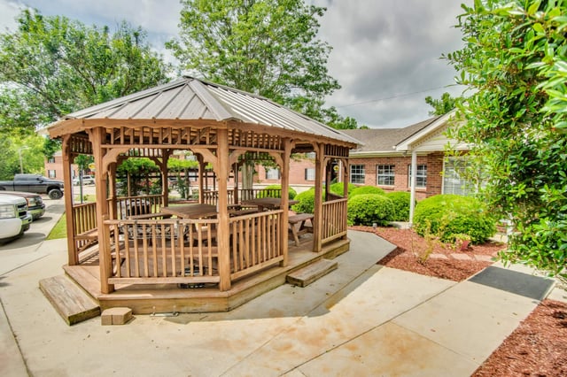 Wooden gazebo with picnic tables in a community courtyard.
