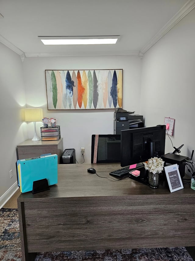 Office desk with computer, printer, and abstract art.