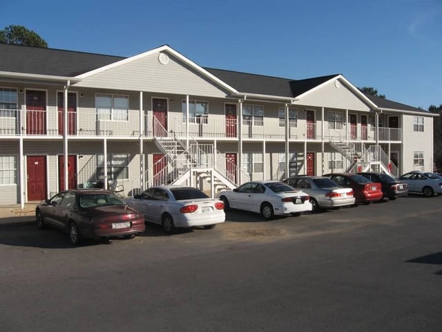 Exterior view of apartment building with parking lot in front.