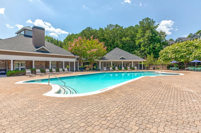 A large, sparkling blue swimming pool with a hot tub and lounge chairs.