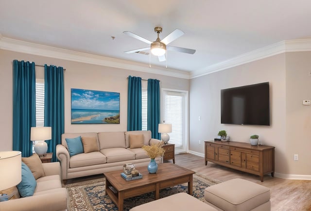 Living room with sofas, coffee table, TV, and ceiling fan.