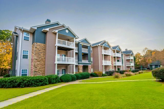 Exterior view of apartment buildings with balconies and manicured lawns.