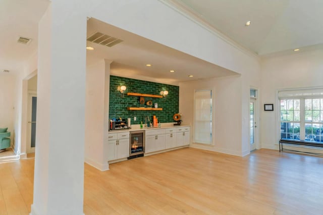 Community wet bar with green tile backsplash and wood shelving.
