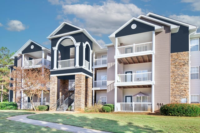 Exterior view of apartment buildings with balconies and green lawn.