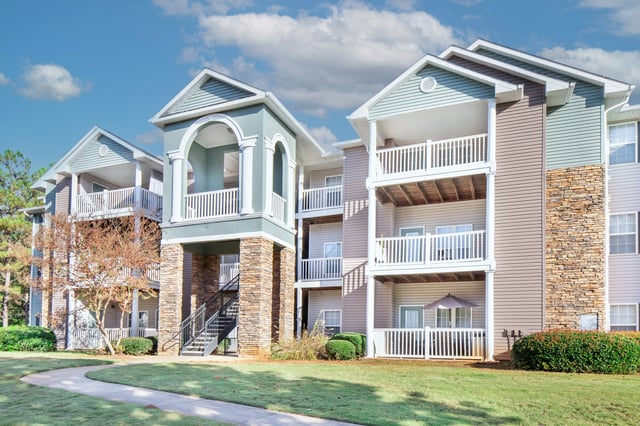Exterior view of apartment buildings with balconies and a pathway.