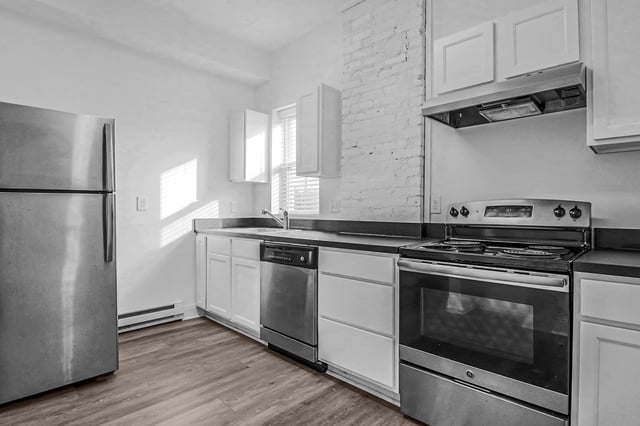 Kitchen with stainless steel appliances including a refrigerator, dishwasher, and oven, as well as white cabinets and countertops.