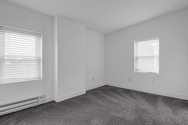 Empty bedroom with two windows and blinds.