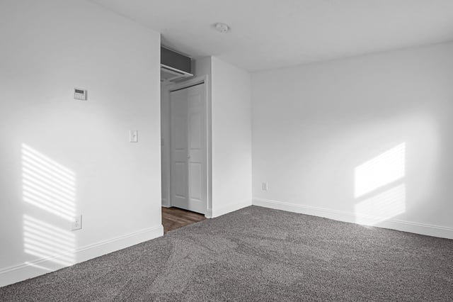 Empty apartment bedroom with gray carpet and white walls.