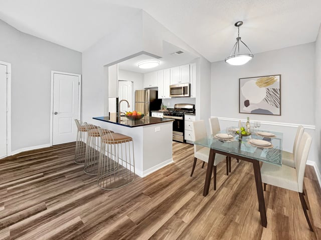 Modern kitchen and dining area with breakfast bar and glass-top dining table.