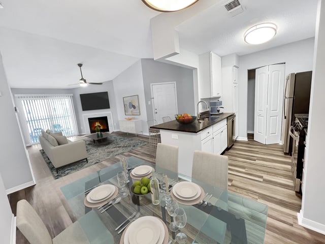 Living room and kitchen area of an apartment with a fireplace and dining table.