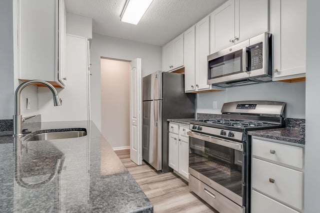Modern kitchen with stainless steel appliances and granite countertops.
