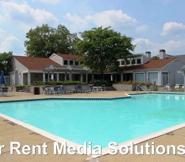 Outdoor swimming pool with lounge chairs and a building in the background.
