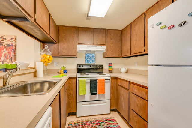 Kitchen with wooden cabinets, white stove, and refrigerator.
