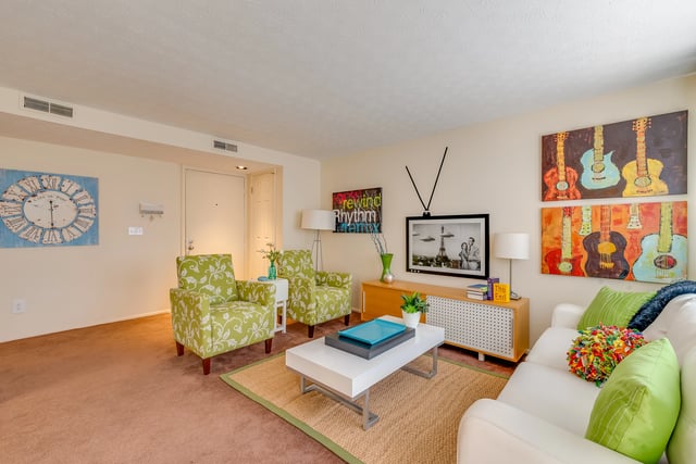 Living room with floral chairs, white sofa, coffee table, and art