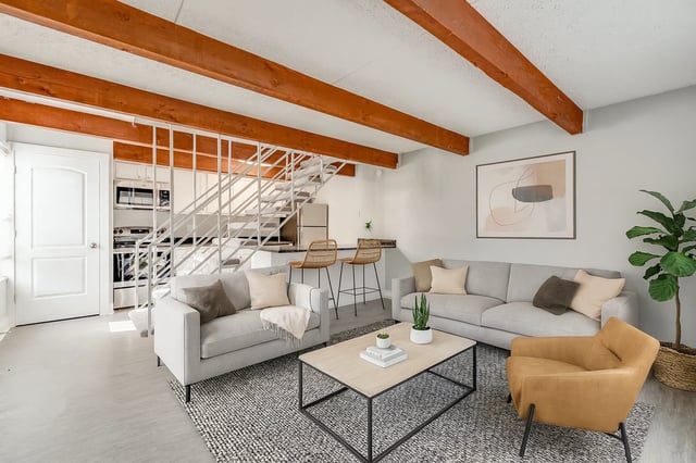 Living room with couches, coffee table, and stairs leading to the kitchen.