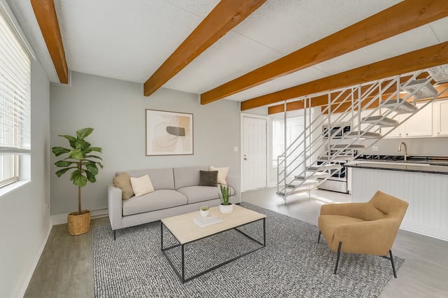 Living room with gray sofa, accent chair, coffee table, and staircase.
