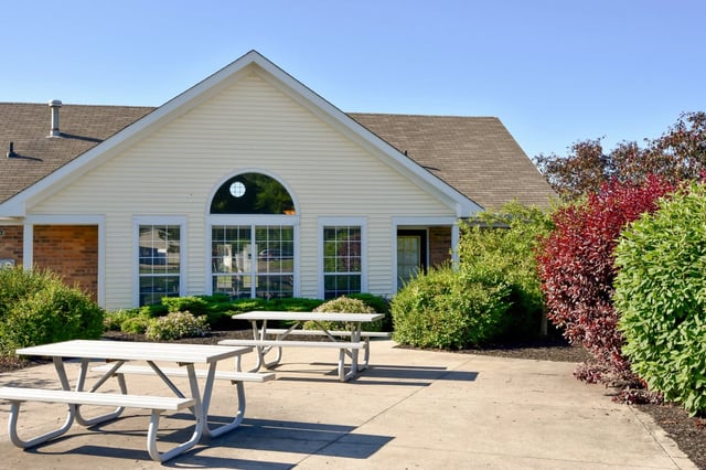 Picnic tables outside a building with landscaping and blue sky.