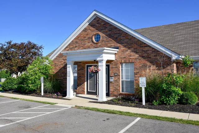 Exterior of a brick building with a covered entrance and landscaping.
